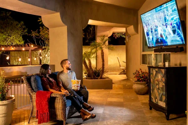 couple watching outdoor TV in shaded patio at night