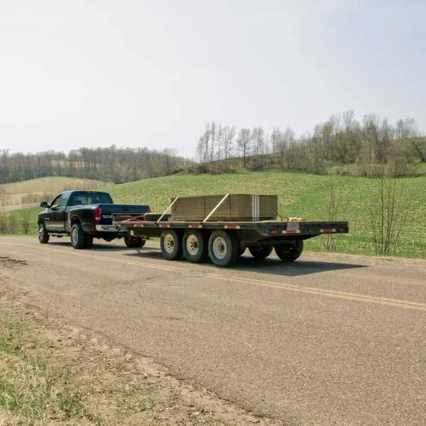 Truck hauling flatbed tri-axle trailer