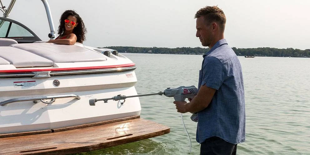Man Using a Power Washer to Maintain Boat while Woman Watches