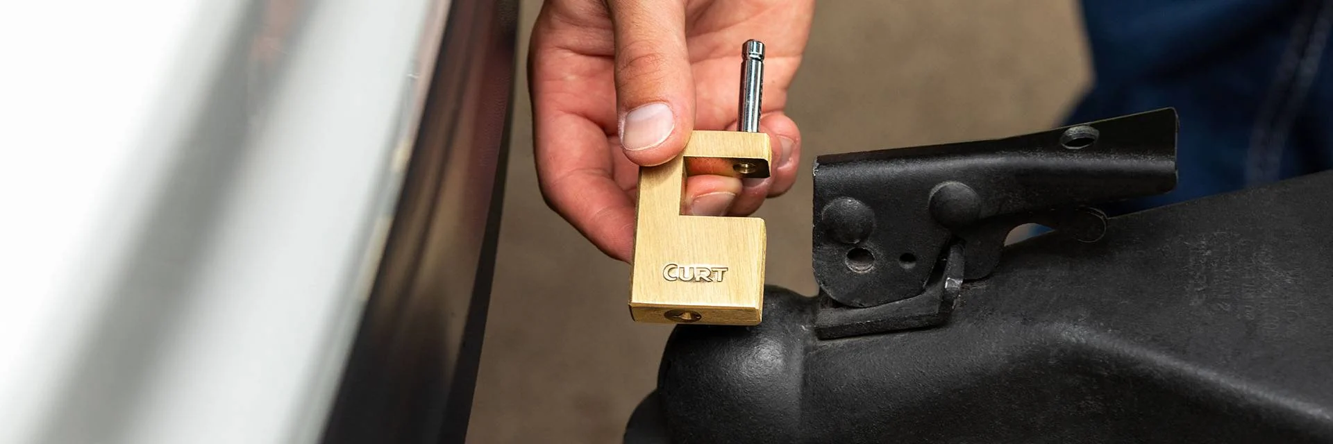 Hand Holding Boat Trailer Lock Next to Boat Trailer Coupler