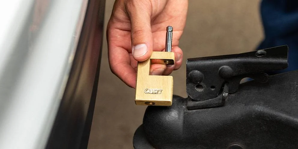 Hand Holding Boat Trailer Lock Next to Boat Trailer Coupler