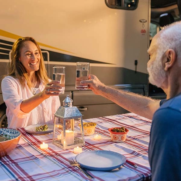 Couple holding glasses of water at picnic table