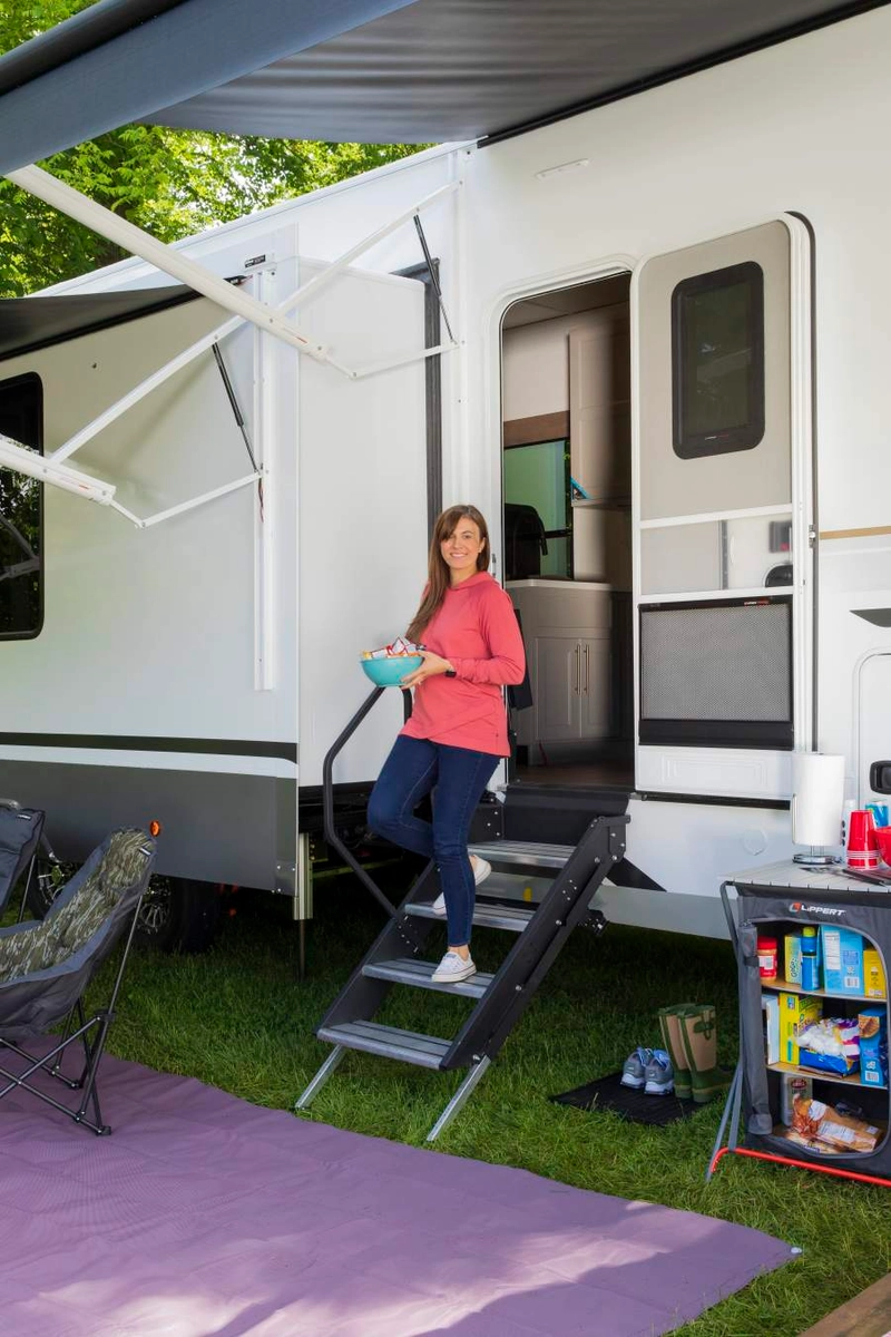 Woman walking down a Lippert Solid Step RV step with easy assist handrail, holding a bowl