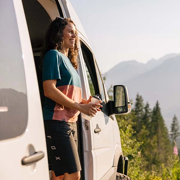 Woman standing in camper van doorway with water bottle